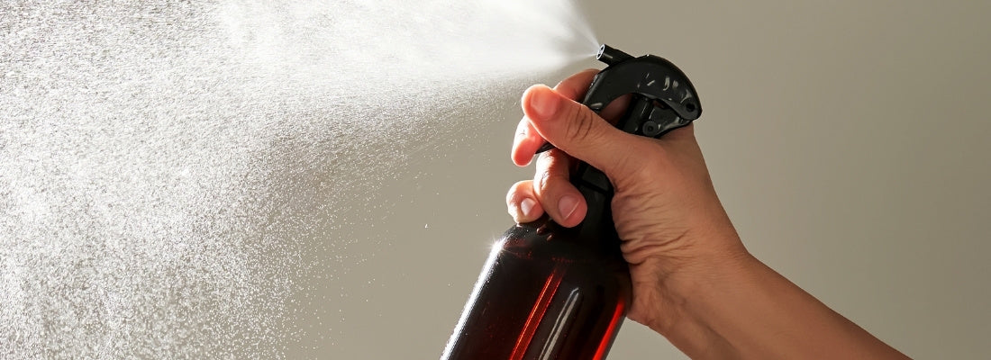 Main vaporisant une brume parfumée avec un flacon pulvérisateur ambré