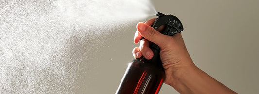 Main vaporisant une brume parfumée avec un flacon pulvérisateur ambré