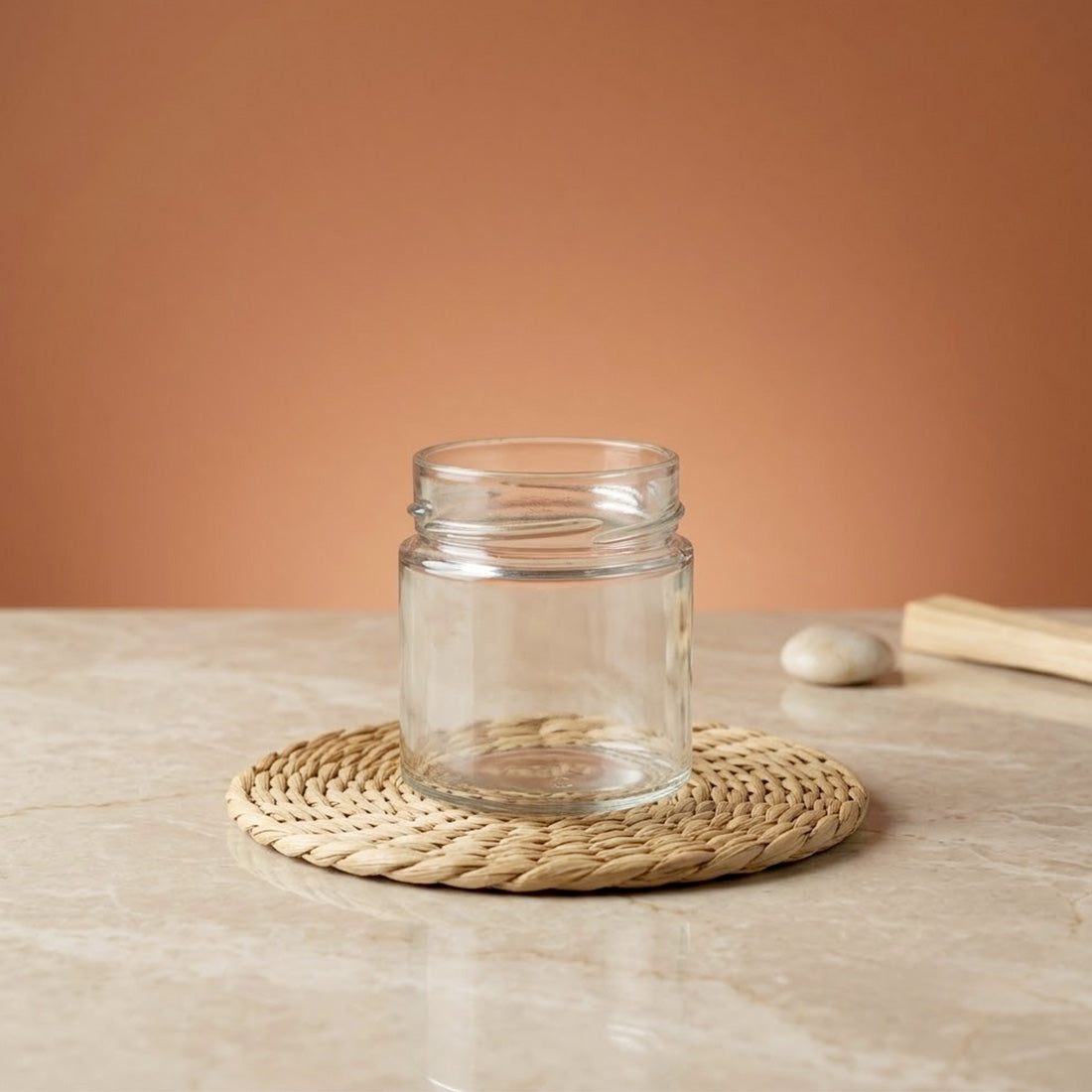 Bocal à bougie transparent de 212 ml vide, posé sur un set en fibre naturelle