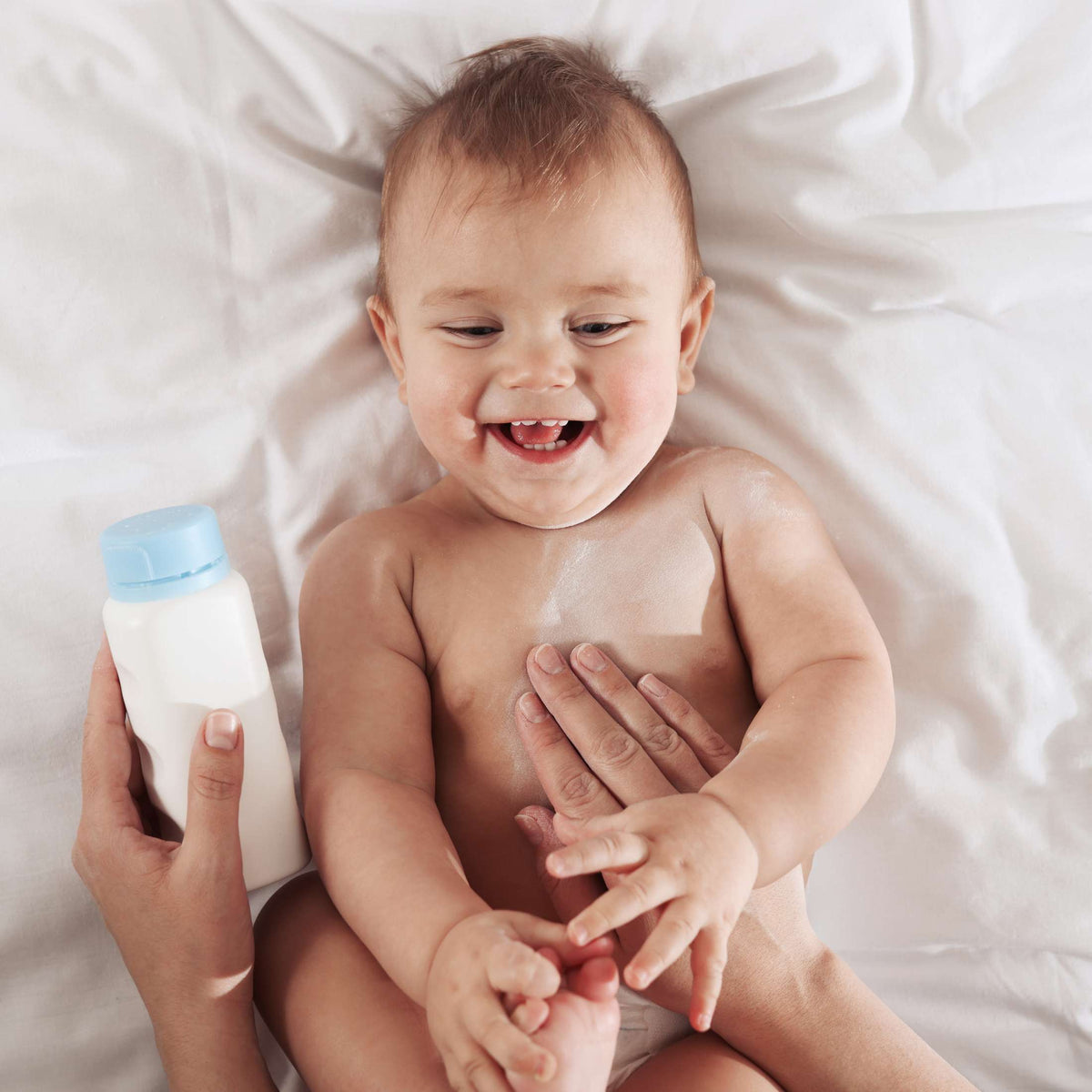 Bébé souriant tenant un flacon de talc, ambiance du parfum Talco