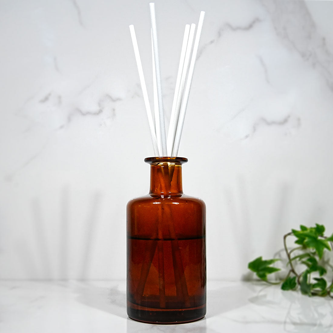 Diffuseur en verre ambré garni de tiges en fibre blanche