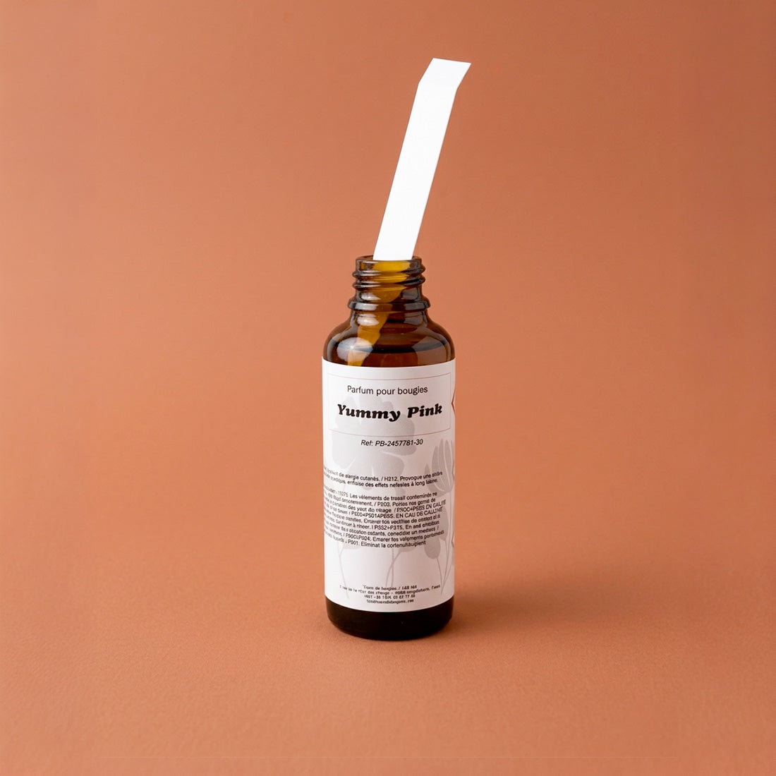 Flacon de parfum ambré avec une touche à sentir posée sur le col