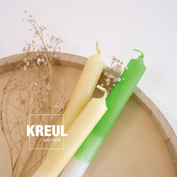 Bougies coniques vertes et crème décorées au stylo, présentées sur un plateau